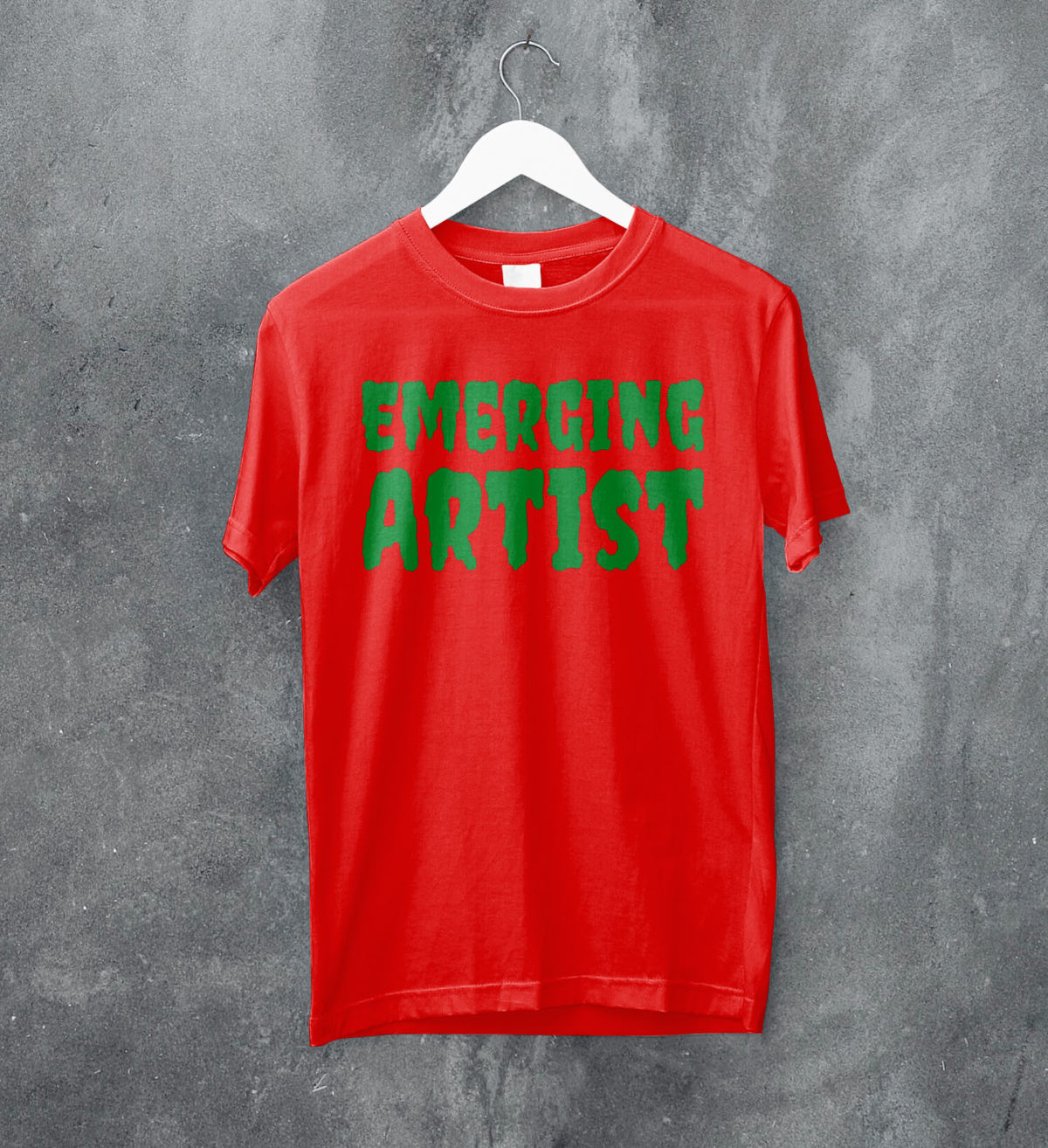A photo of a red T-shirt with the words 'Emerging Artist' in a horror-film typeface printed on it in lurid green ink